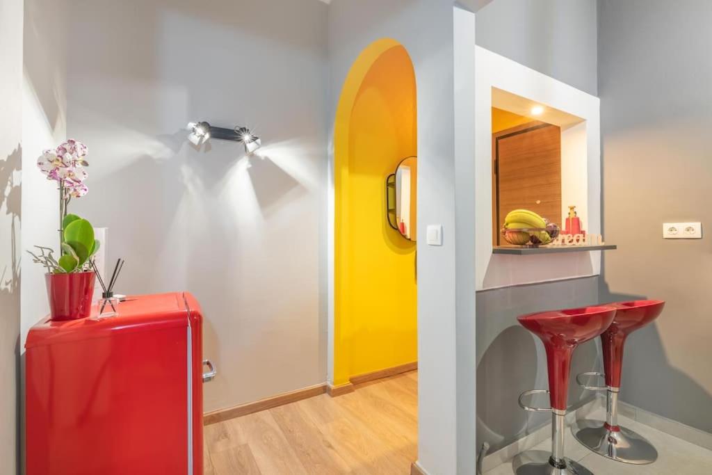 una stanza con una valigia rossa e una porta gialla di The HostMaster Hollywood Space Studio ad Atene