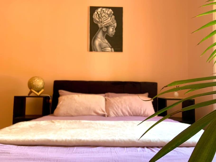 1 dormitorio con 1 cama con una pintura en la pared en Bungalow x Garten & Terrasse x WLAN x europäisch, en Moshi
