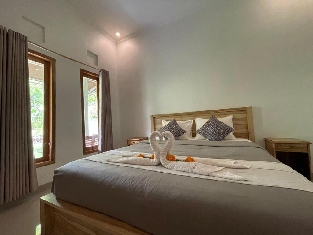 Hello Penida House في نوسا بينيدا: غرفة نوم مع اثنين من مناشف البجع على سرير