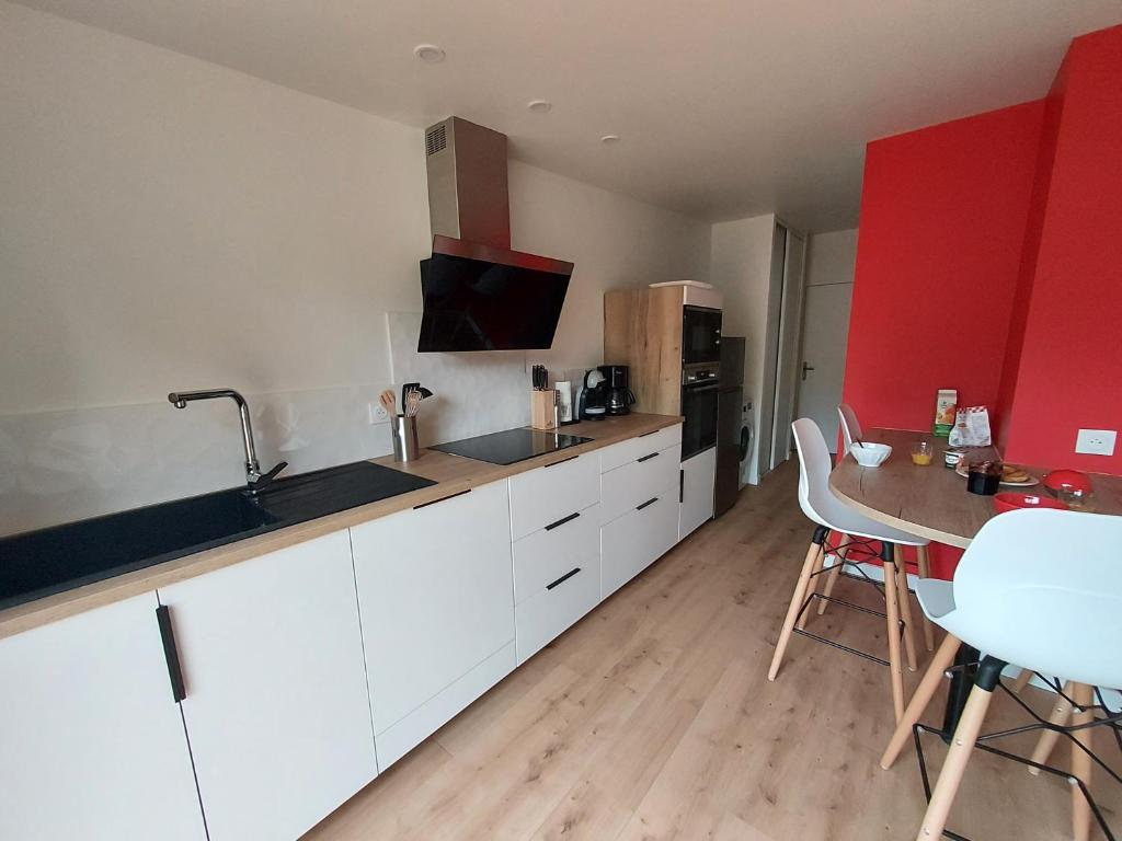 a kitchen with white cabinets and a table with chairs at La Clé du Chesnot in Saint-Quentin-sur-le-Homme