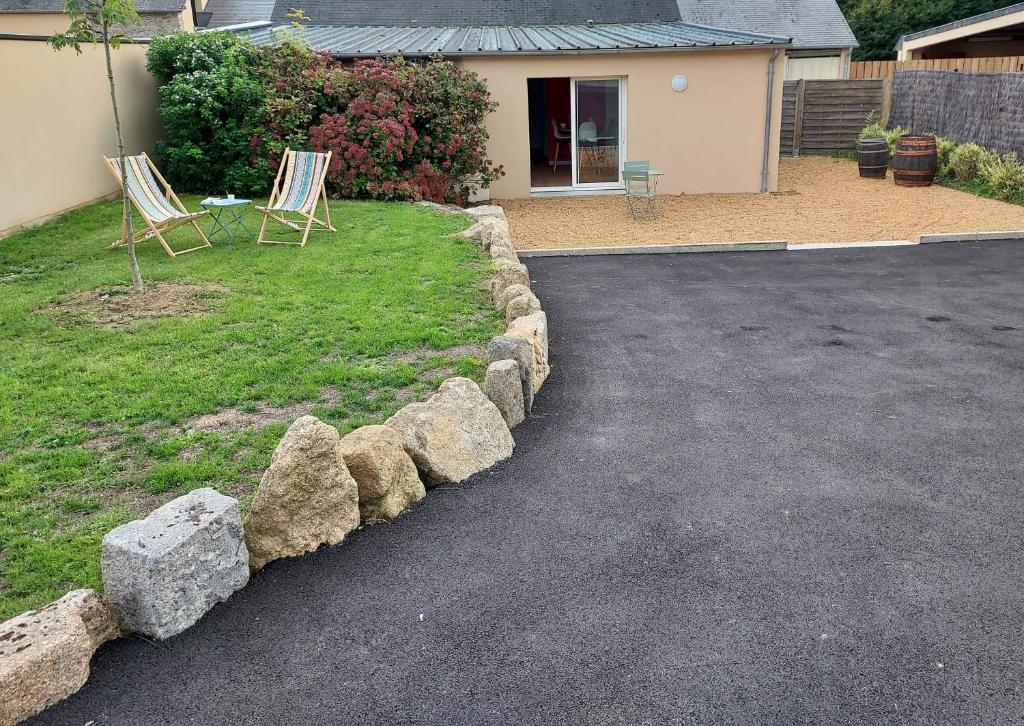 a driveway with two chairs and rocks in front of a house at La Clé du Chesnot in Saint-Quentin-sur-le-Homme