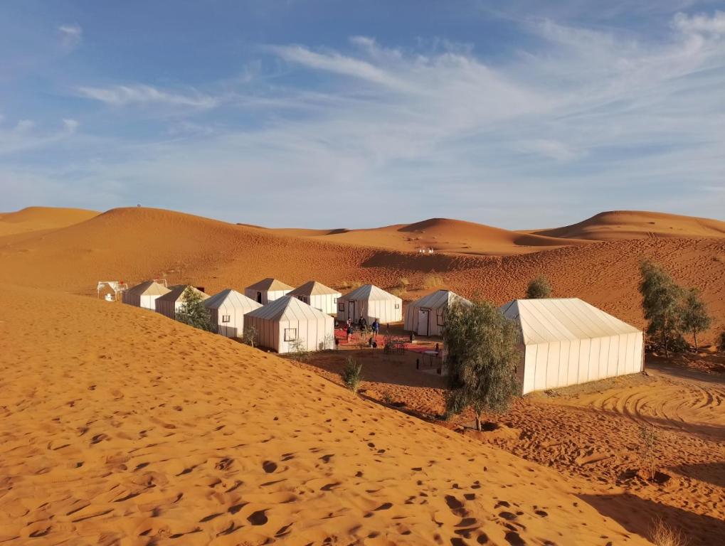 uma fila de casas no deserto perto da areia em Magic Luxury Camp em Merzouga