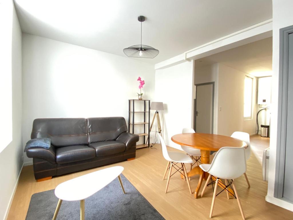 a living room with a black leather couch and a table at Le Sarcoui - Appartement tout confort proche de la Gare in Clermont-Ferrand