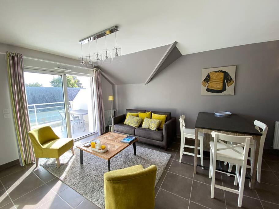 a living room with a couch and a table and chairs at Superbe appartement terrasse, proche de la plage in Bénodet