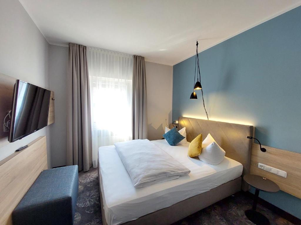 クルムバッハにあるホテル プルッカーのベッドとテレビが備わるホテルルームです。
