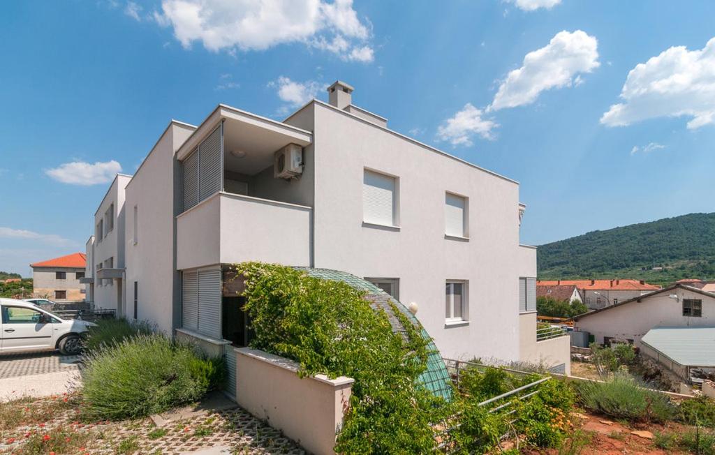 biały dom z zaparkowanym przed nim samochodem w obiekcie Apartman Paiz w mieście Stari Grad