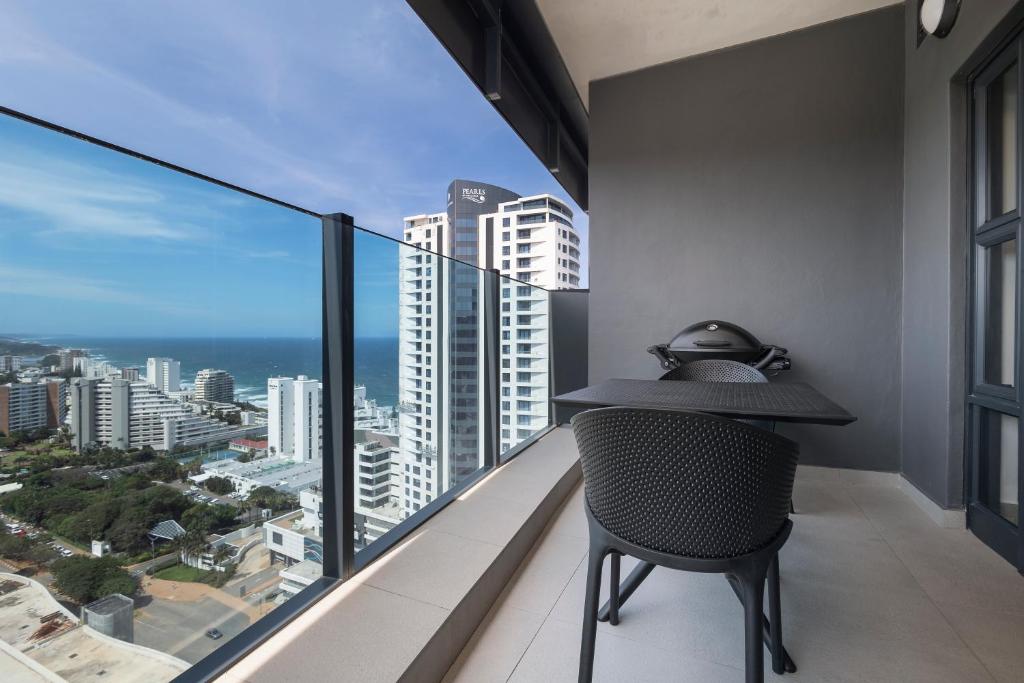 a room with a table and a chair on a balcony at 2202 Oceans Apartment - by Stay in Umhlanga in Durban