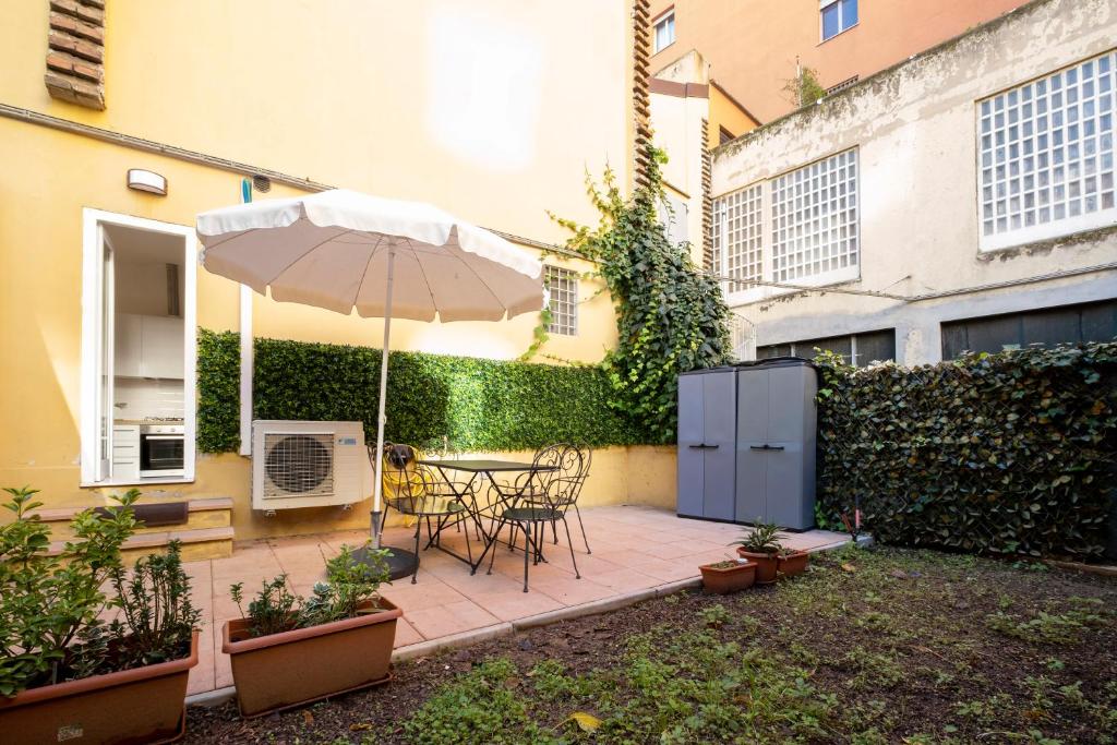 eine Terrasse mit einem Sonnenschirm, einem Tisch und Stühlen in der Unterkunft GetTheKey Boldrini Lofts in Bologna