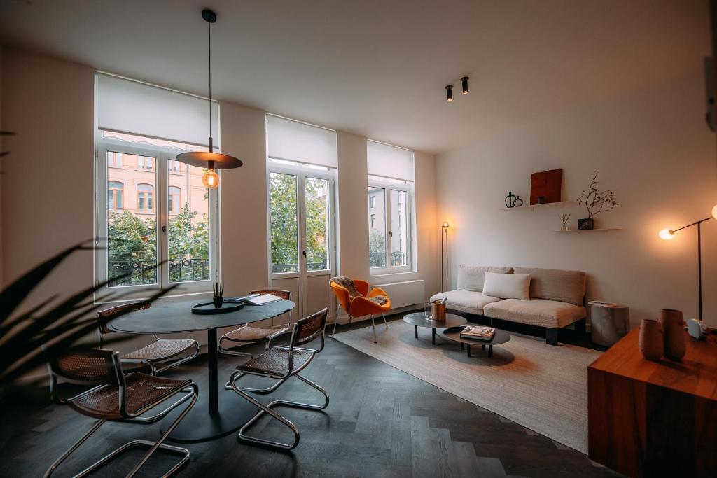 een woonkamer met een tafel en stoelen en een bank bij Sud d'Anvers in Antwerpen