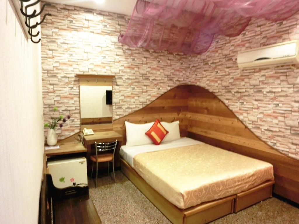 a bedroom with a bed and a brick wall at Xing Ji Hotel in Kenting