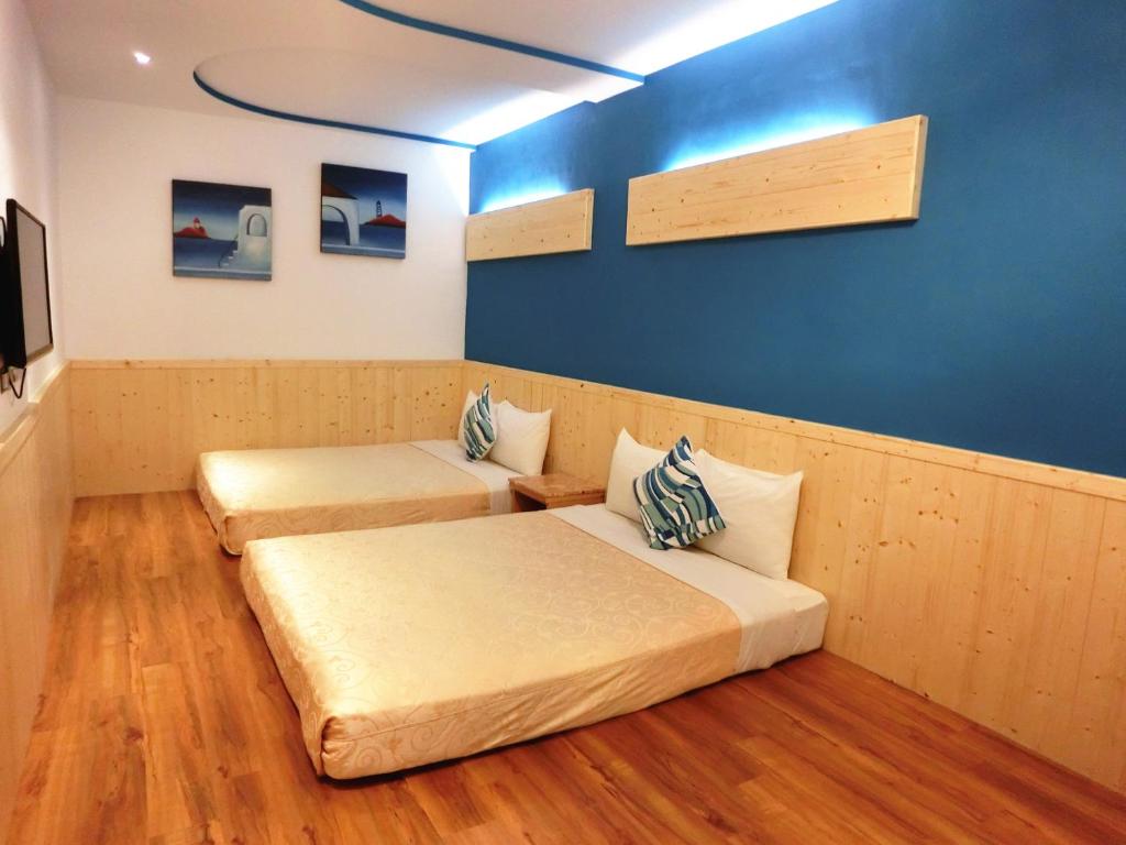 a room with two beds and a blue wall at Xing Ji Hotel in Kenting