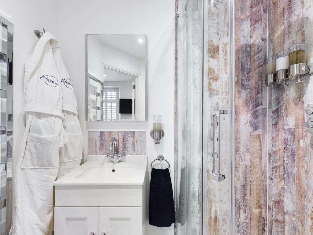 a white bathroom with a sink and a shower at Driftwood Boutique Guest House in Rhosneigr