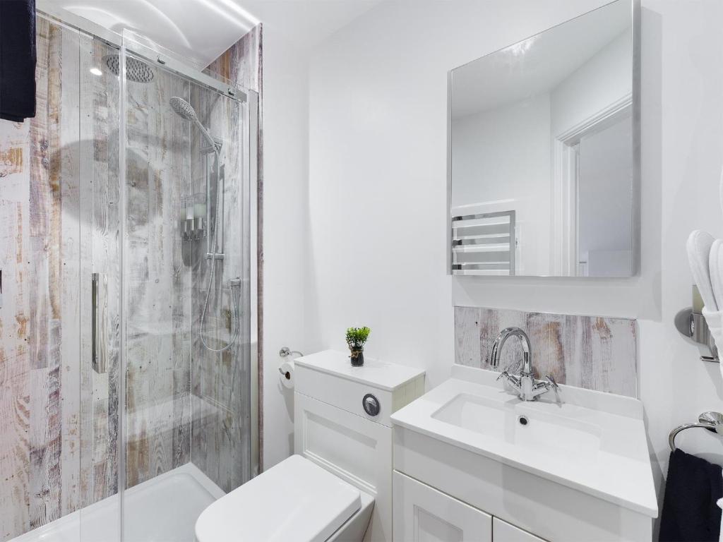 a white bathroom with a sink and a shower at Driftwood Boutique Guest House in Rhosneigr