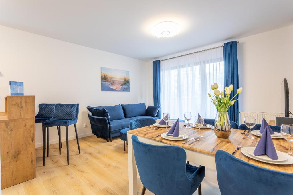 een eetkamer met een tafel en stoelen en een bank bij Ambria Apartments Platan Complex II in Świnoujście