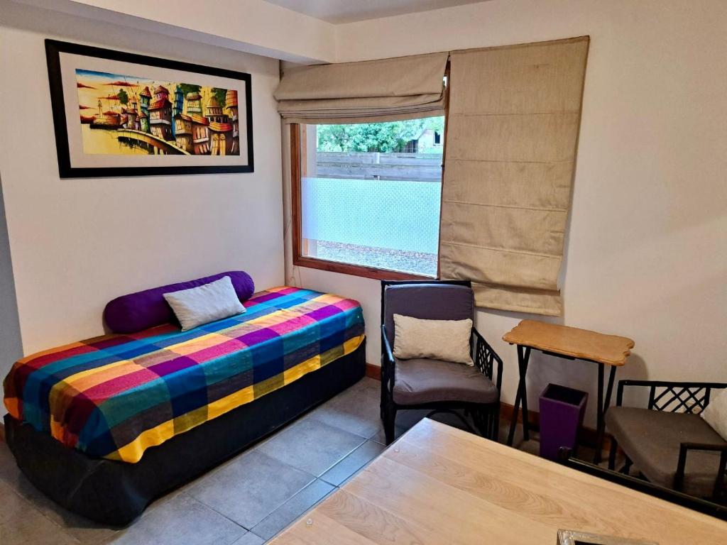 Schlafzimmer mit einem Bett, einem Tisch und einem Fenster in der Unterkunft Departamento M&L in San Martín de los Andes
