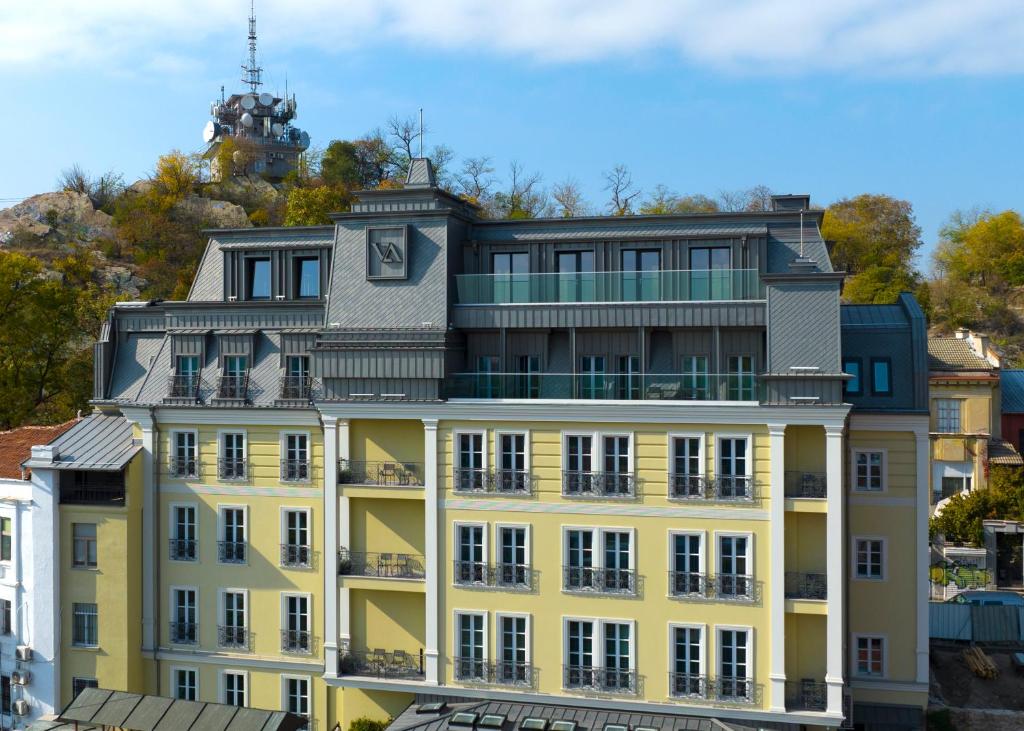 a yellow building with a clock on the top of it at VIZUALIZA Residence Hotel in Plovdiv