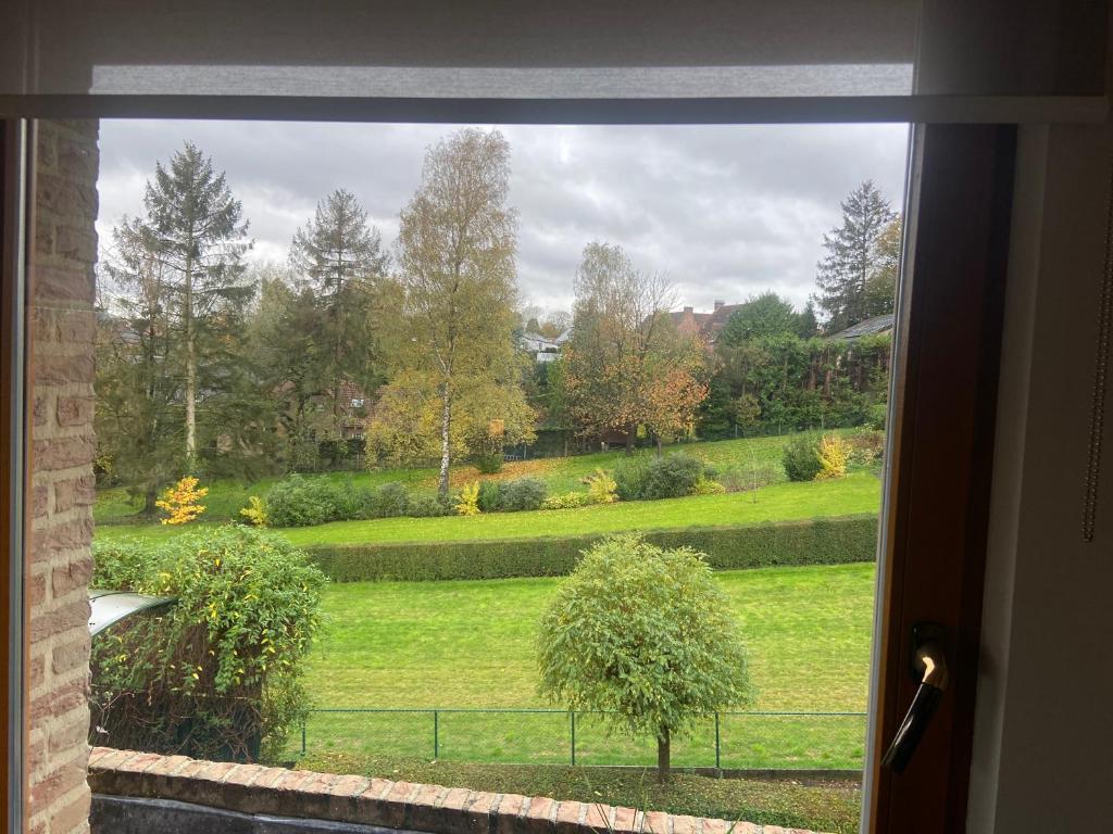 een raam met uitzicht op een tuin vanuit een huis bij La Clé des Champs in Tervuren