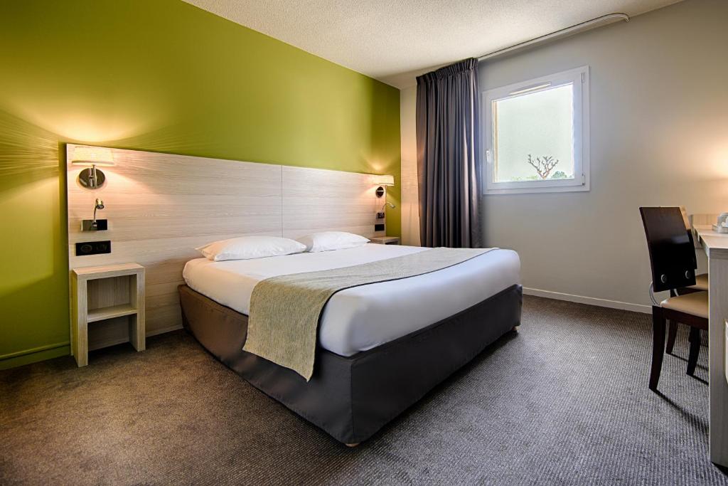 a hotel room with a large bed and a window at The Originals City, Hôtel Les Bruyères, Dax Nord (Inter-Hotel) in Castets