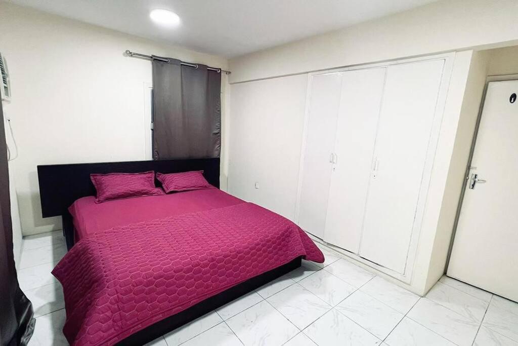 a bedroom with a bed with a pink comforter at 1 Room in apartment available for rent dating not allowd in Sharjah