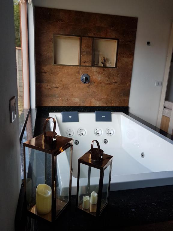 uma banheira branca com 2 mesas na casa de banho em Chalé Canto do Galo 1 em Gonçalves
