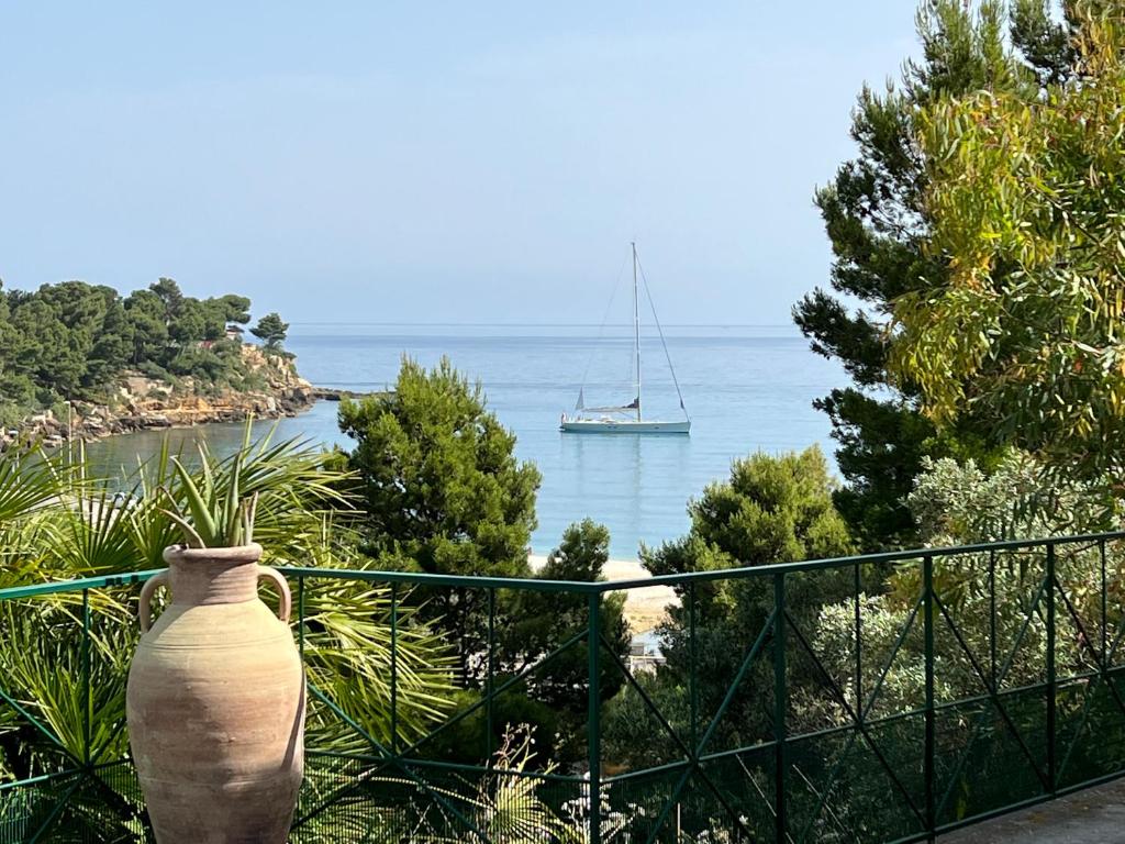a large vase sitting on a fence with a boat in the water at TORRE MARIZA Guidaloca in Scopello