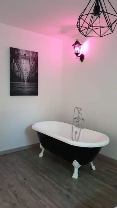 - une baignoire noire et blanche dans une chambre avec des lumières roses dans l'établissement Dépendance au 1er étage d 'une jolie fermette., à Mignères