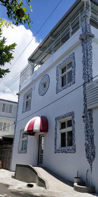 a white building with a red and white awning at Home in Hengchun Homestay in Hengchun South Gate