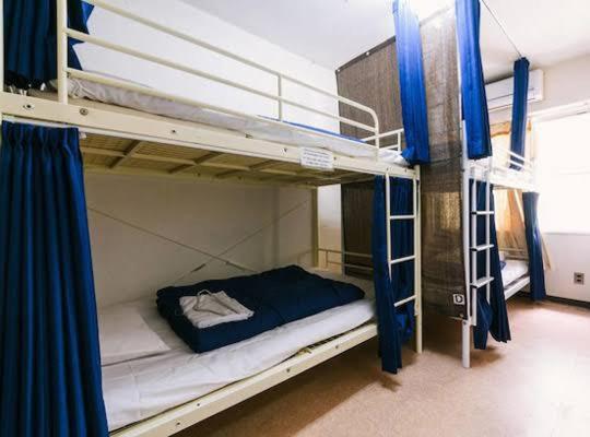 a bedroom with two bunk beds with blue curtains at Shinjuku Hostel in Tokyo