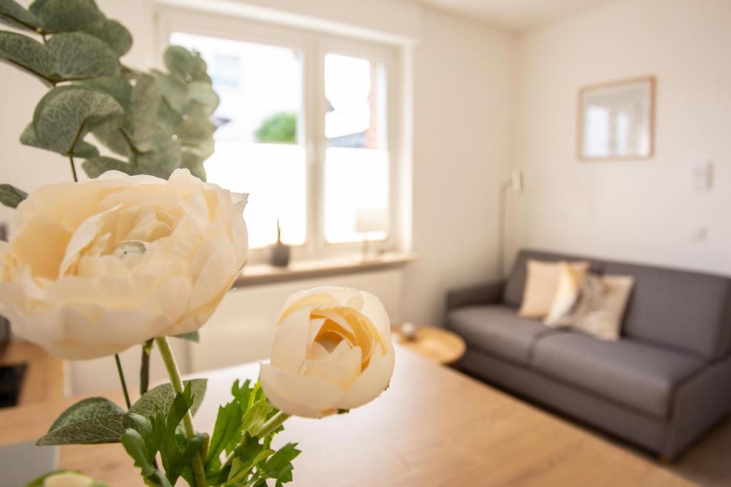 sala de estar con sofá y mesa con una flor en boardinghouse44, en Georgsmarienhütte