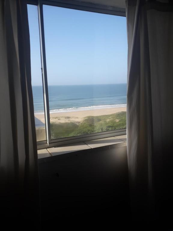 a window with a view of the beach at Breezy Seaview-On the Beach- Open balcony in Amanzimtoti