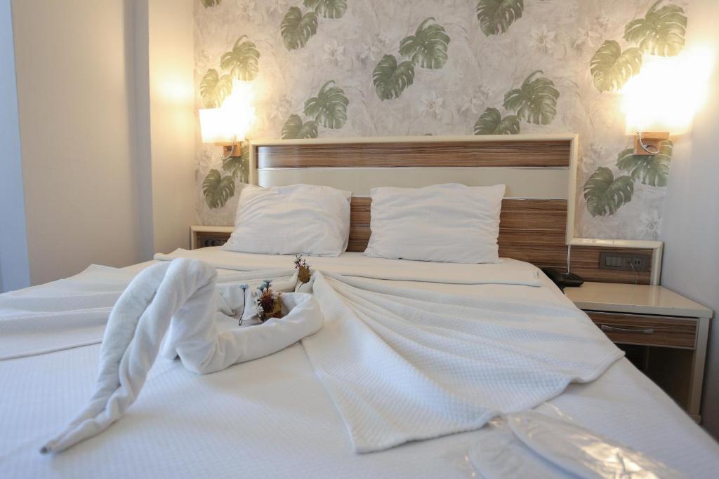 a large white bed with white sheets and pillows at BEST SMYRNA HOTEL in Aydın