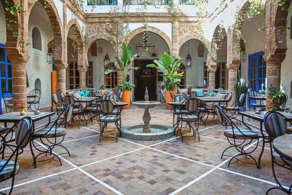 une cour avec des tables, des chaises et une fontaine dans l'établissement Riad Al Madina, à Essaouira