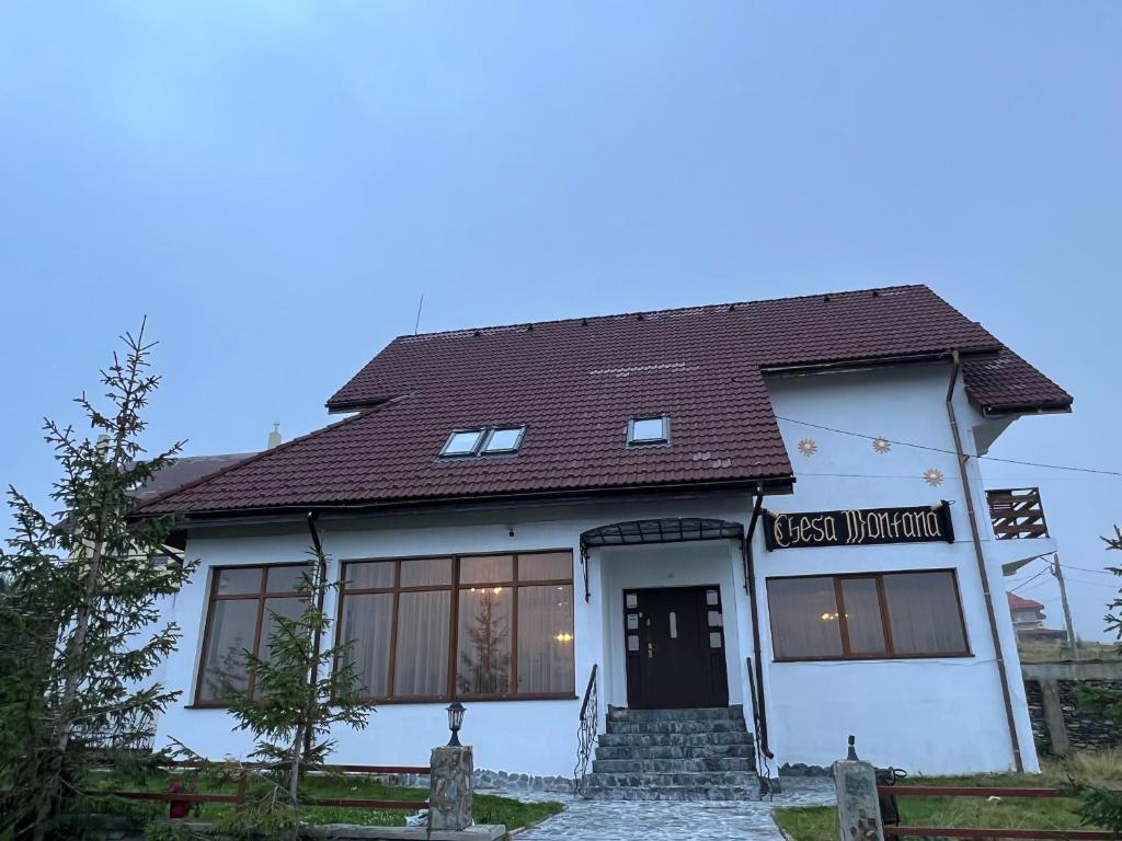 ein weißes Haus mit braunem Dach in der Unterkunft Chesa Montana in Ranca