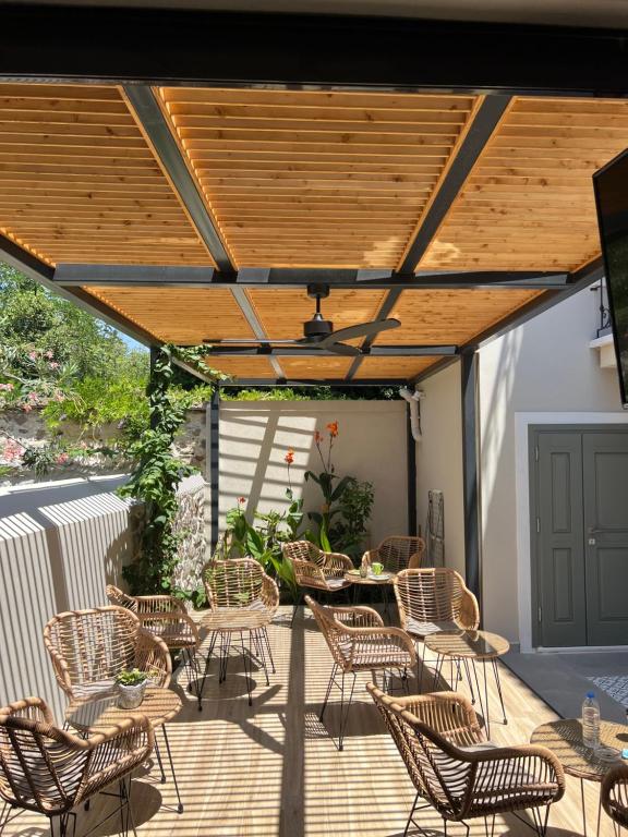 a patio with chairs and tables under a wooden pergola at Aesthesis Arxontiko Luxury Rooms in Myrina