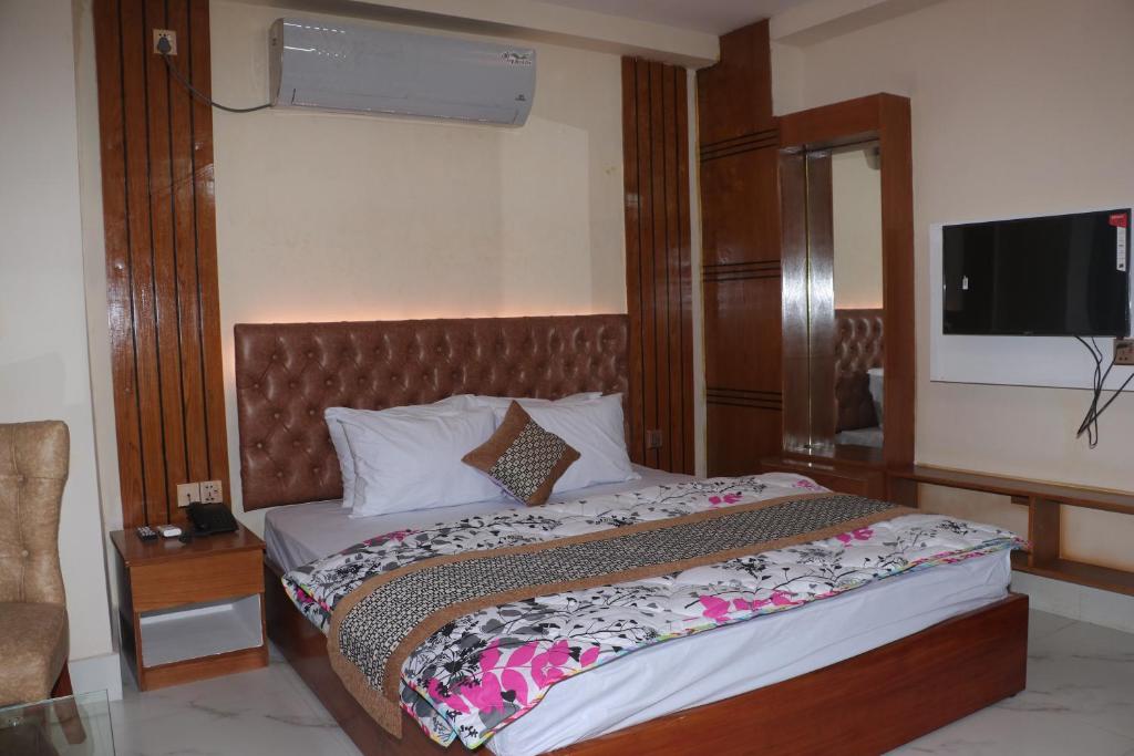 a bedroom with a bed with a television on the wall at Hotel Blue Moon in Chittagong