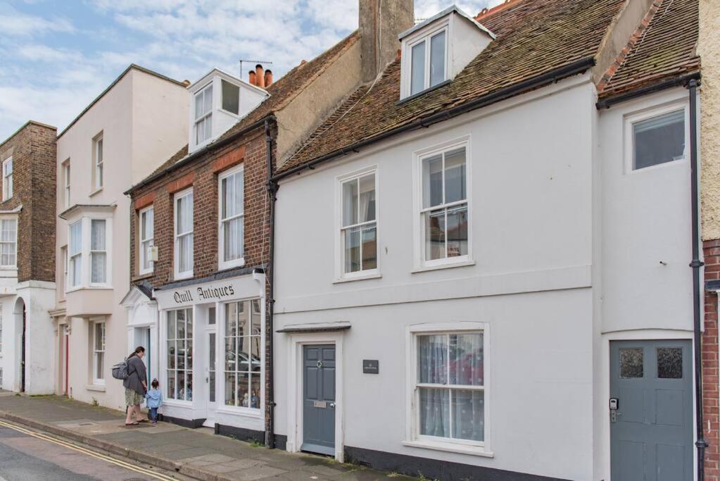 a person walking down a street with white houses at Lighthouse Cottage in Deal