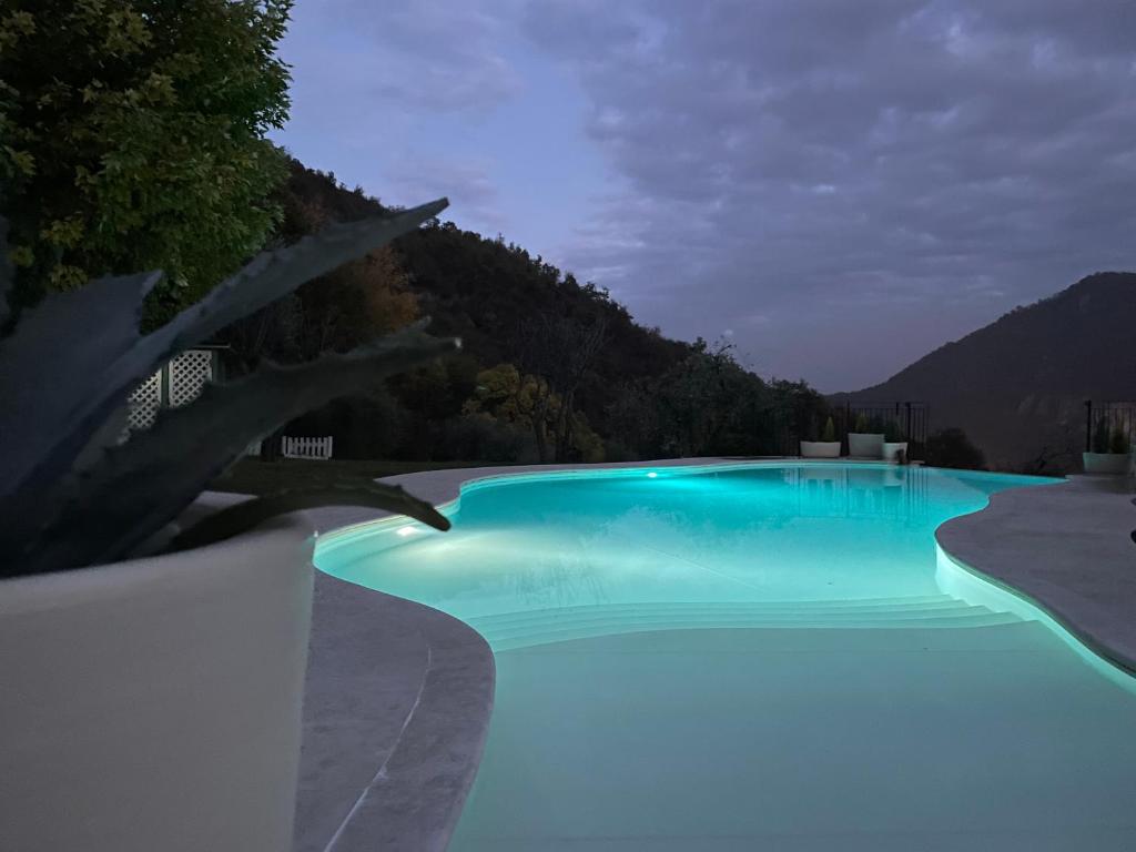 a blue swimming pool with a mountain in the background at CHALET VELA Natura e Relax in Gavardo