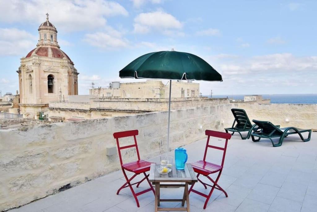 une table avec des chaises et un parasol sur le toit dans l'établissement Vallettastay- Lucky Star Penthouse 501, à La Valette