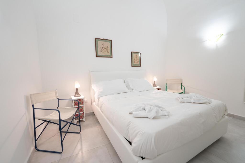 um quarto branco com uma cama branca e uma cadeira em Vico Amico by Dimorra em Nápoles