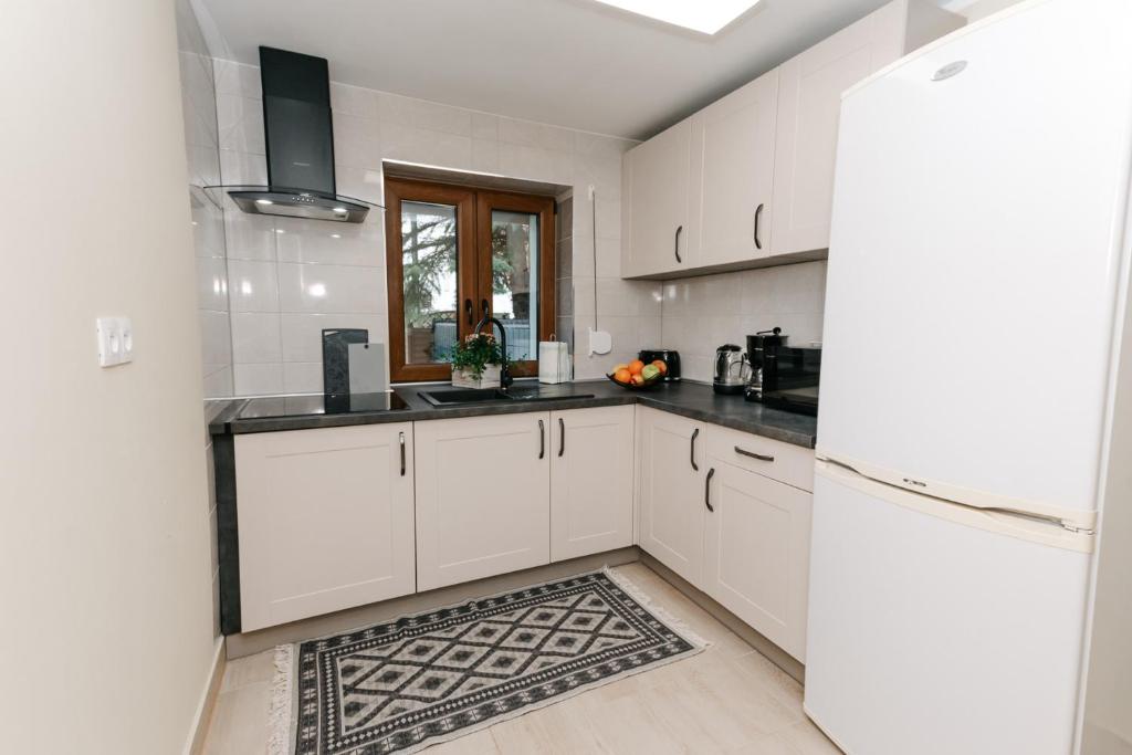 a kitchen with white cabinets and black counter tops at Apartament KARO 1 Karkonosze in Jelenia Góra