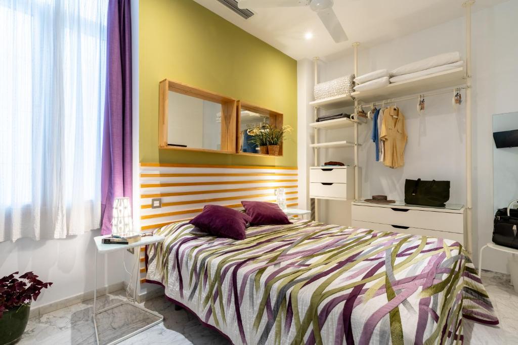 - une chambre avec un lit doté d'oreillers violets dans l'établissement Sevilla Central Suites Apartamentos Puerta Jerez, à Séville