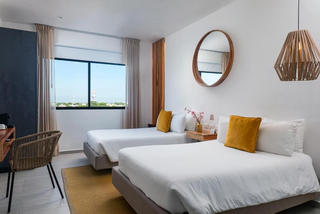 a hotel room with two beds and a mirror at Balkon Boutique Hotel in Playa del Carmen