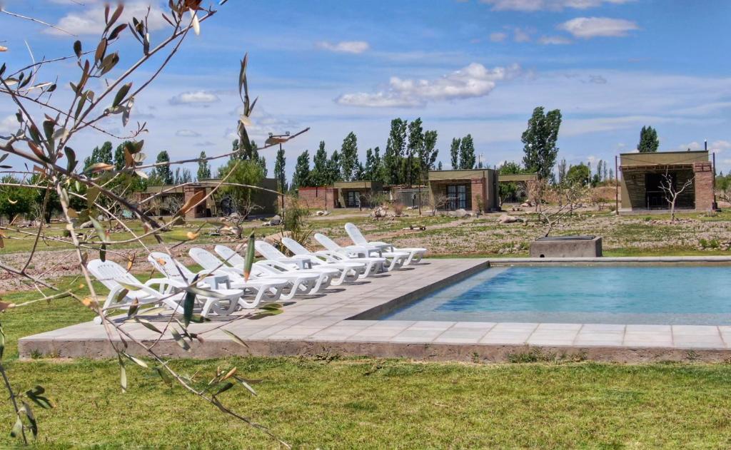 a group of white lounge chairs next to a pool at Complejo Turístico Chachingo in Maipú