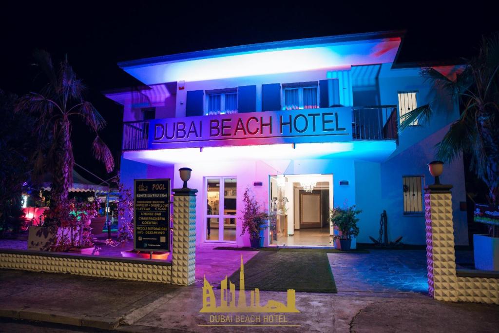 DubaiBeachotel في ليدو ديلي ايستينسي: فندق اضاءه بالليل مع وجود لافته مكتوب عليها فندق شاطئ مزدوج