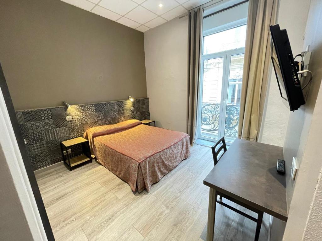 Schlafzimmer mit einem Bett, einem Tisch und einem Fenster in der Unterkunft Hotel de La Comédie in Montpellier