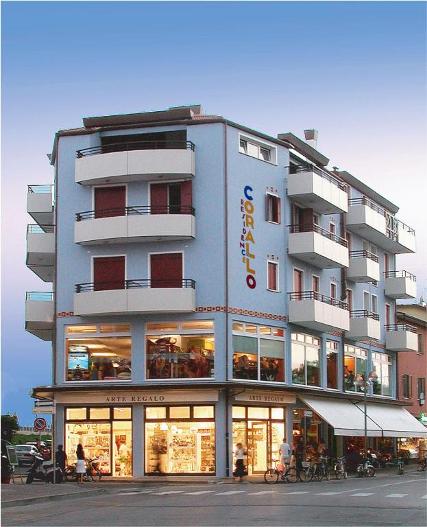 ein großes Gebäude, vor dem Menschen sitzen. in der Unterkunft Residence Corallo in Caorle