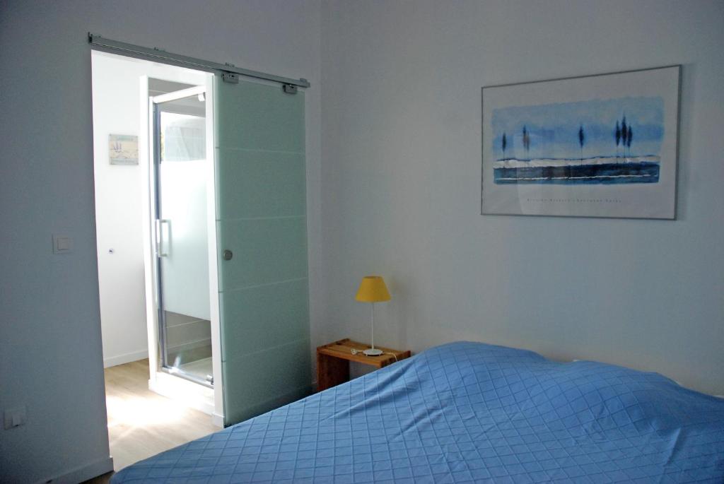 sypialnia z niebieskim łóżkiem i lustrem w obiekcie Le Mas de la Palmeraie - Appartement dans propriété privée au calme avec piscine et tennis w mieście Bormes-les-Mimosas