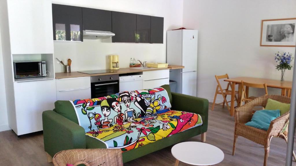 salon z zieloną kanapą i kuchnią w obiekcie Le Mas de la Palmeraie - Appartement dans propriété privée au calme avec piscine et tennis w mieście Bormes-les-Mimosas