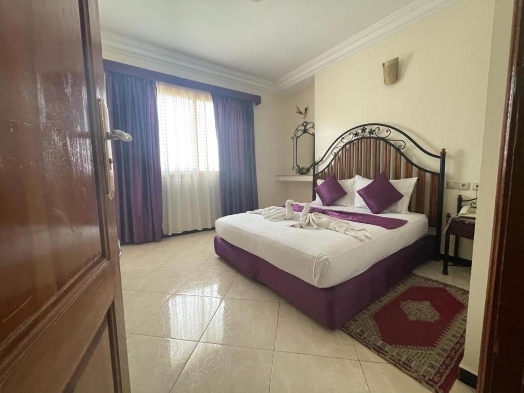 1 dormitorio con 1 cama grande con almohadas moradas en Perla Hôtel, en Fez