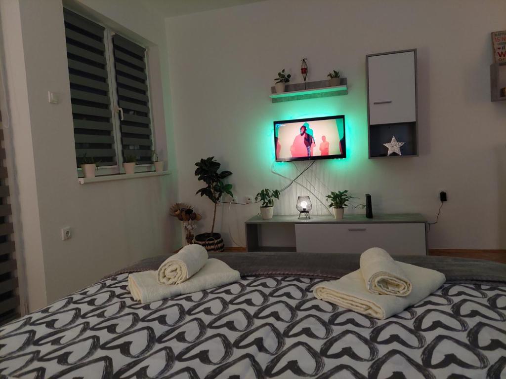 a bedroom with a bed with two towels and a television at Apartman Bart in Subotica